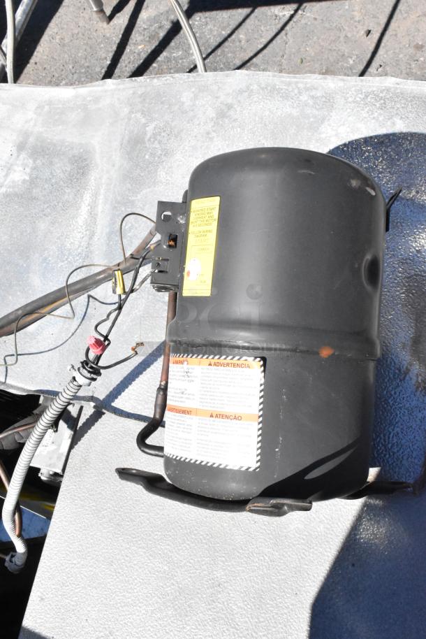 Norlake self-contained walk-in freezer with Norlake CPF060DC-A compressor, 115/208-230V, 1 phase. Visible warnings on unit.