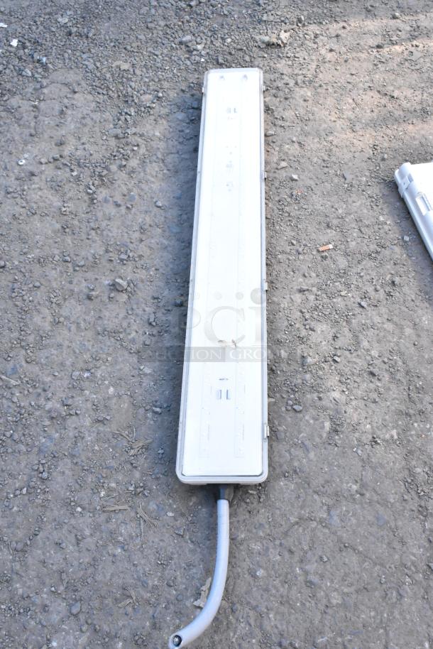 Kason light fixture on gravel, rectangular with visible wiring, used condition, no visible damage, auction item.