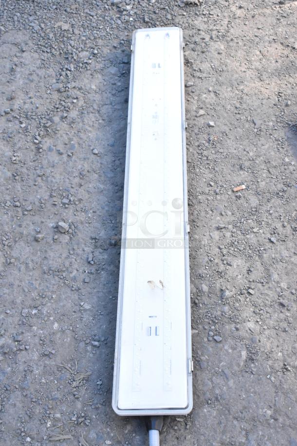 Two Kason light fixtures with a rectangular design, metal casing, and electrical connections, good condition, on a rocky surface.