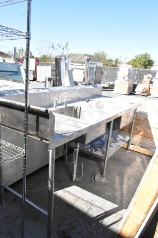 Stainless steel table with sink basin, faucet, handles, drawer, and under shelf. Features durable construction. Suitable for industrial use.