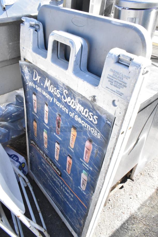 Assorted items including a weathered Signacade Deluxe sign frame with Dr. Moss Seamoss poster.
