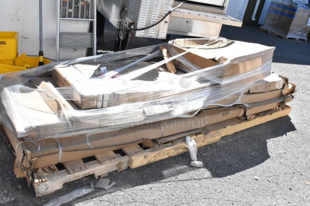 Five new scratch and dent items, including work tables, on a pallet wrapped in plastic. Some boxes slightly damaged.