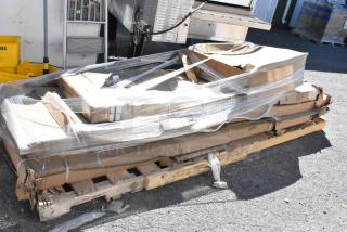 Five new scratch and dent items, including work tables, on a pallet wrapped in plastic. Some boxes slightly damaged.
