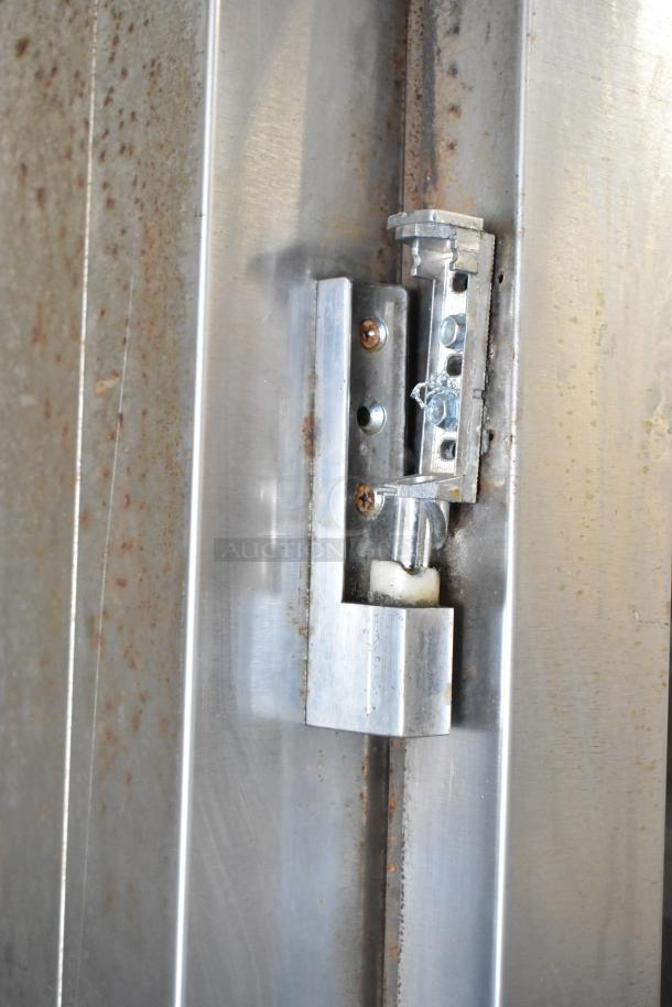 Close-up of a Baxter stainless steel component on a commercial gas-powered mini rotating rack oven, showing a hinge detail with some rust.