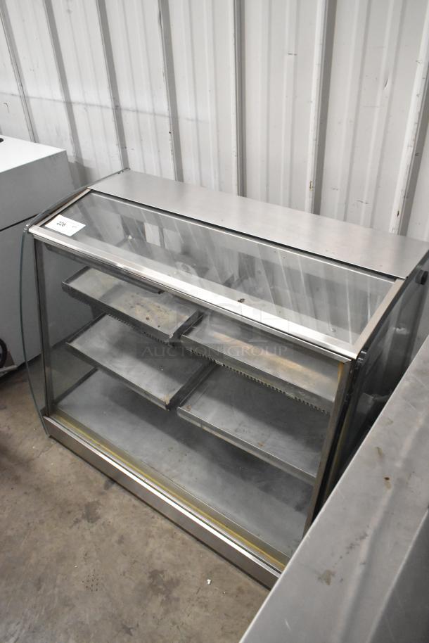 Metal commercial countertop display case with glass panels, three shelves, and a stainless steel frame. Good condition.