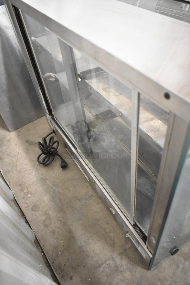 Metal commercial countertop display case with glass panels. Features sliding doors and interior shelving. Power cord included.
