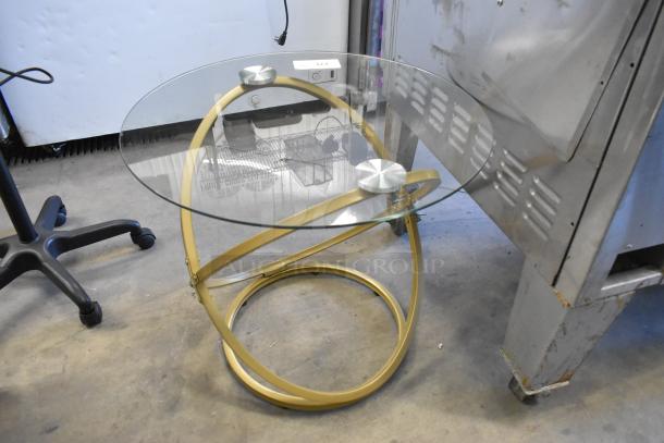 Modern gold finish table with a circular glass countertop, featuring a unique intertwined base. Excellent condition.