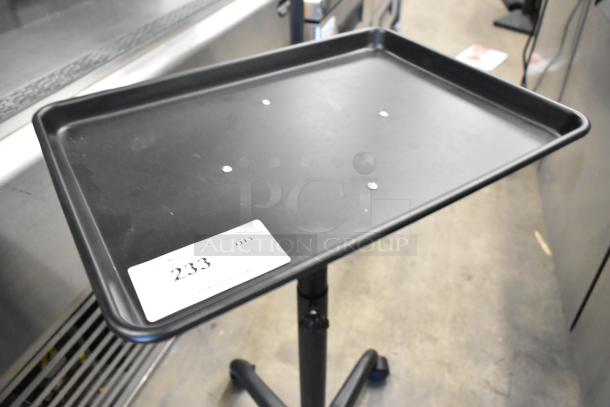 Black tray dolly on casters with adjustable height stand. Auction tag 233 visible. Good condition.
