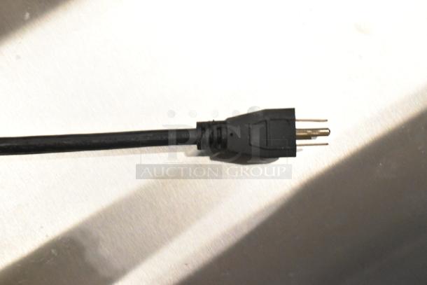 Close-up of a power cord plug for the Waring WSM20LT Luna 20 Quart Planetary Dough Mixer. Black cord, standard plug.