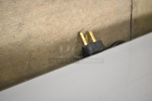 Close-up of black and gold electrical plug for ServIt 423EST4WO500 steam table, showing minor scratches on a white surface.