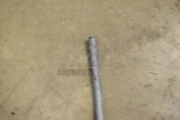 Blurred image of a gray rod-like object on a beige surface.