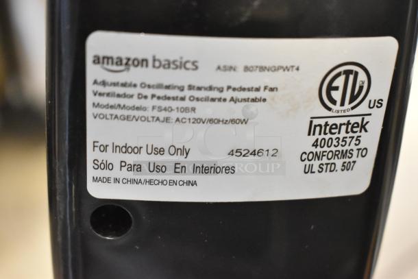 Two Amazon Basics FS40-10BR floor-style fans, 120V, 1 phase, with oscillating feature. For indoor use only. Model details shown.