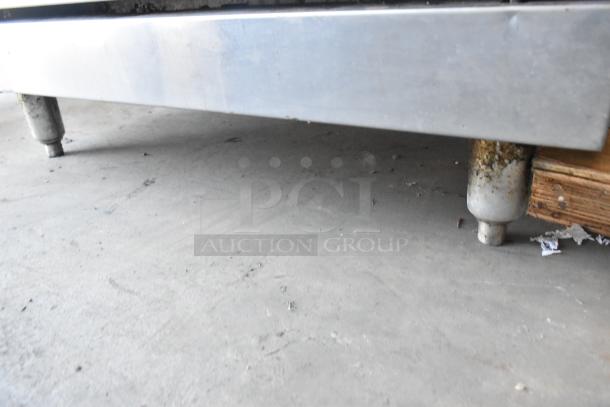 American Range stainless steel gas 6-burner commercial range with oven, visible legs show some rust, indicating wear.
