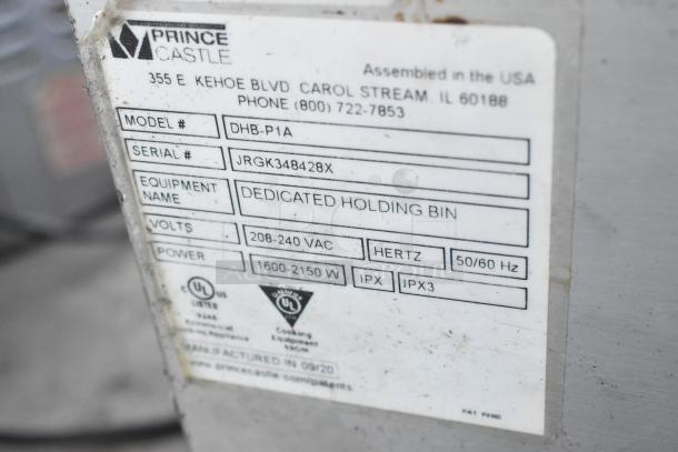 Prince Castle DHB-P1A stainless steel countertop holding bin label, showing model, serial number, voltage, and power details.