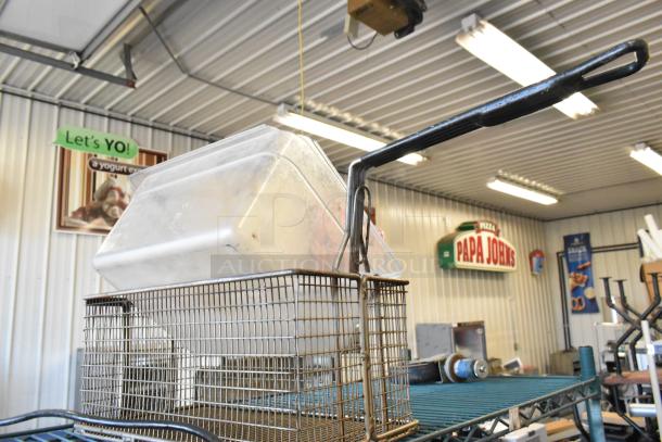 Lot featuring a metal fry basket, white poly bin, and a motor, all in used condition, displayed on a metal rack.