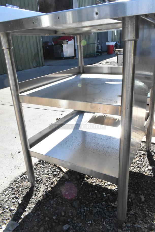 Stainless steel soda station with sturdy under shelves, outdoor setting, visibly weathered surface. Suitable for commercial use.