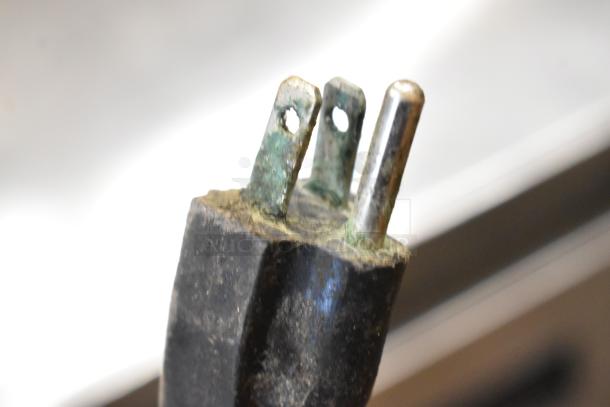 Damaged power plug with corrosion on metal prongs, close-up view.