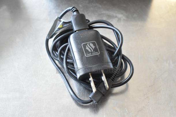 Black Skull Shaver branded charger with cord for Pitbull Gold Pro PBG4-8700, new condition, on stainless surface.