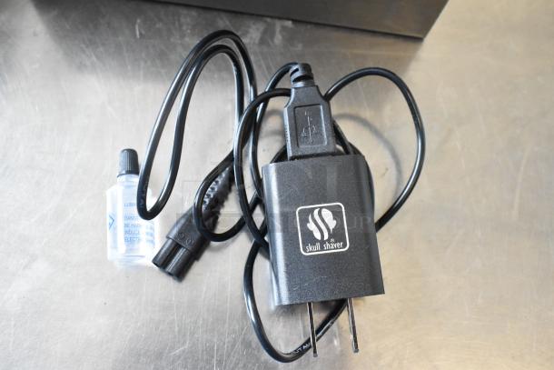 Charger and lubricant bottle for Pitbull Gold Pro PBG4-8700 head and face shaver, new condition with Skull Shaver logo.