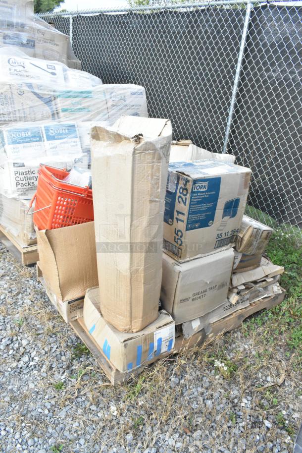 Pallet with various boxes labeled "Tork," "Noble," containing food processor blades, floor mat, glasses, casters, some new, some damaged.