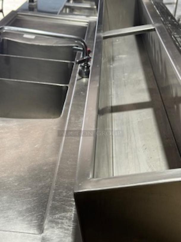 Three-compartment stainless steel commercial sink with adjacent two-door cooler. Suitable for restaurants and bars.