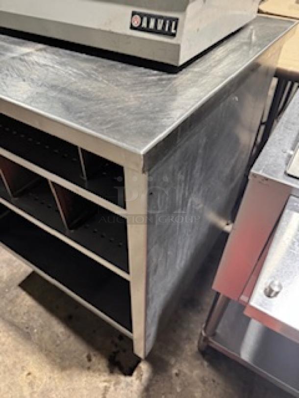 Stainless steel table by S&G Manufacturing, custom design, visible shelves, minor surface scratches.