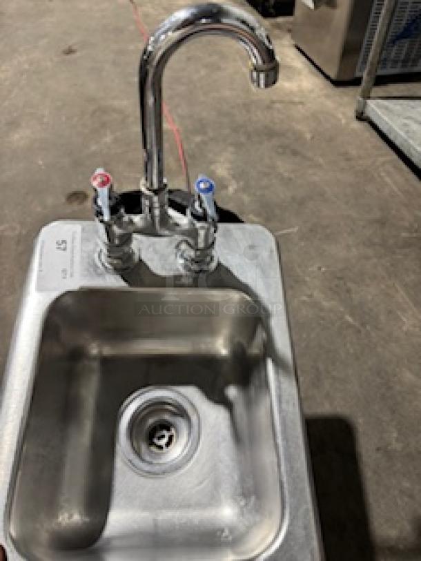 Drop-in single stainless steel sink with dual-handle chrome faucet, used condition, visible drain and fixture details.