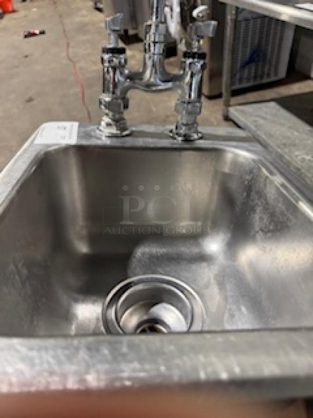 Stainless steel drop-in single sink with faucet, lightly used, dual handles, shiny finish, suitable for kitchens or commercial use.