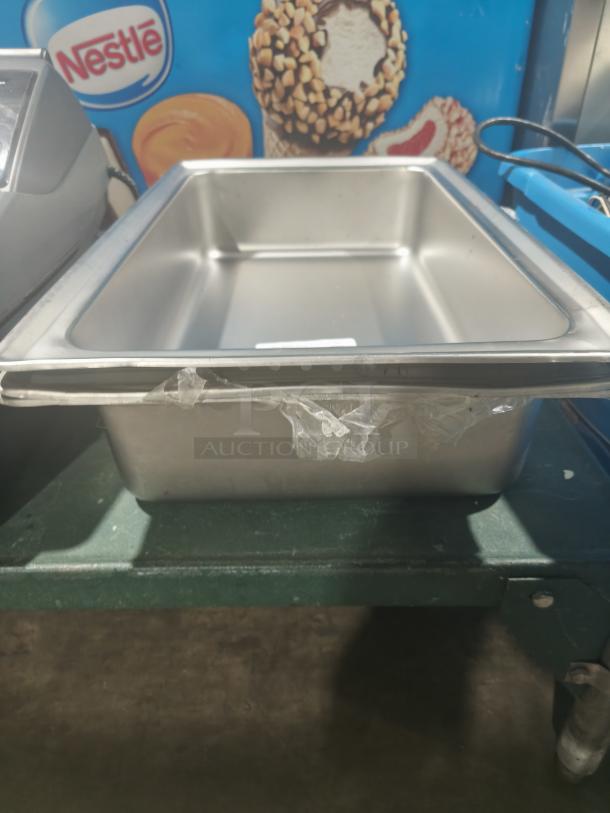 Stainless steel full-size hotel pan, 4" deep, in good condition. Visible protective film partially intact.