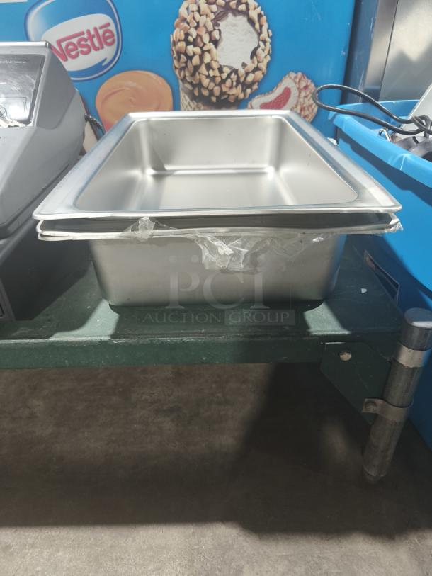 Stainless steel full-size hotel pan, 4" deep, used condition, slight surface wear. Ideal for commercial kitchen use.