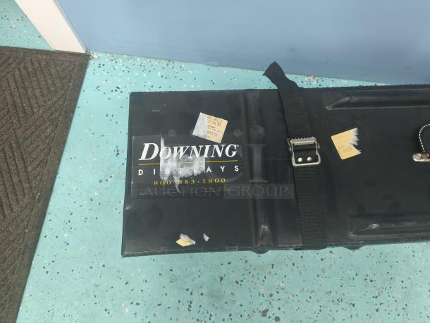 Downing Displays hard-sided trade show shipping case, black with straps, features logo and contact number, used condition.