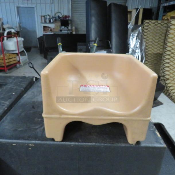 Dual-sided booster seat, beige plastic, good condition, visible warning label on seat back.