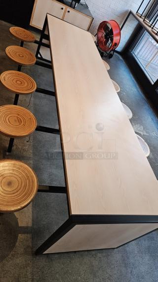 Wooden and metal table with ten attached stool seats, 143x30x30 inches. Modern design, excellent condition.