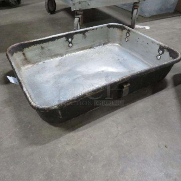 Rectangular metal roaster pan, weathered finish, with handles. Visible signs of use; no visible labels or markings.