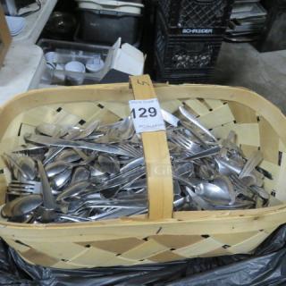 Assorted flatware in a wooden basket, mixed condition, ideal for collectors or resellers. Marked tag "129 PCI Auctions."
