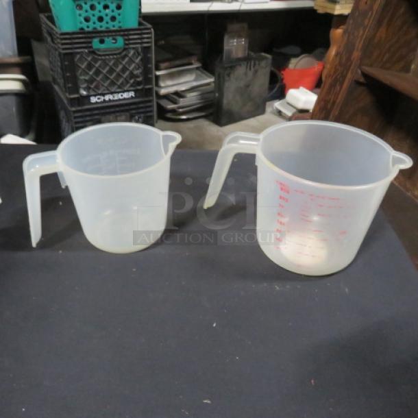 Two opaque plastic measuring cups with ergonomic handles, varying sizes, and red measurement markings.