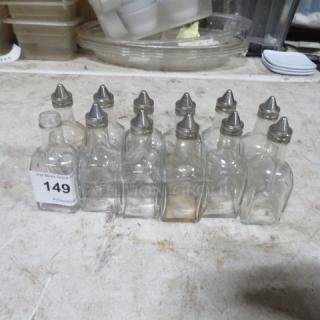 Lot of 12 glass vinegar bottles, one missing lid. Includes metal caps, some bottles have visible wear. Auction tag 149 attached.