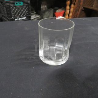 Clear glass rocks glass on a dark surface, featuring a smooth finish and cylindrical shape, in excellent condition, no visible markings.