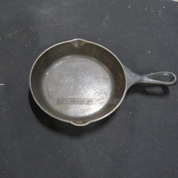 6.5-inch cast iron skillet, showing signs of wear, with pour spouts and traditional handle; model 3XBID.