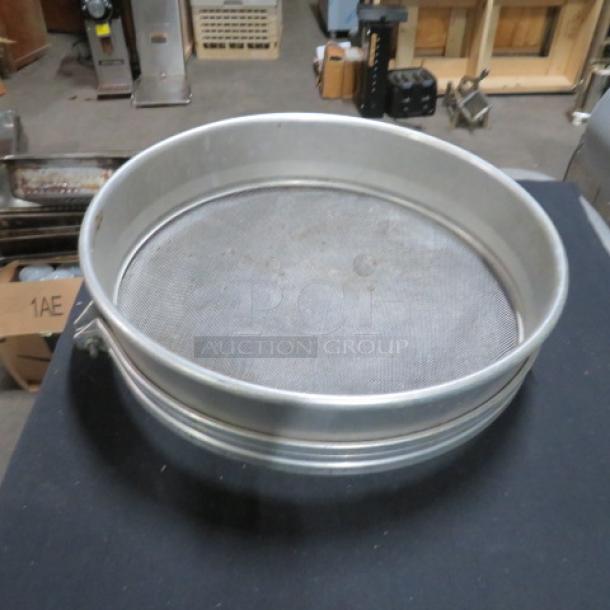 17-inch metal sifter, circular design, fine mesh screen, good condition, suitable for kitchen or industrial use.