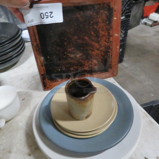 Lot of assorted dinnerware with plates, a cup, and a ceramic jug. Includes vintage items with varied wear and patina. Item tag reads "250."