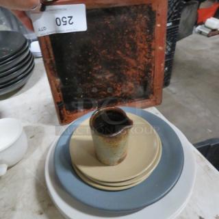 Lot of assorted dinnerware with plates, a cup, and a ceramic jug. Includes vintage items with varied wear and patina. Item tag reads "250."