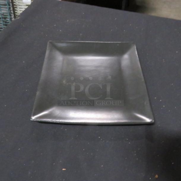8-inch square World Market plate, black, ceramic, gently used with minor scuffs, smooth finish.