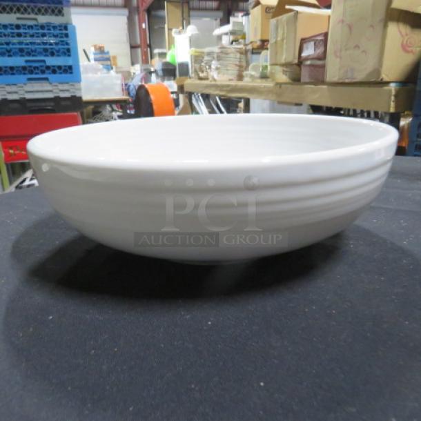 White 9-inch Fiesta bowl, gently used. Smooth finish with subtle ridges, in a storage setting. Ideal for collectors.