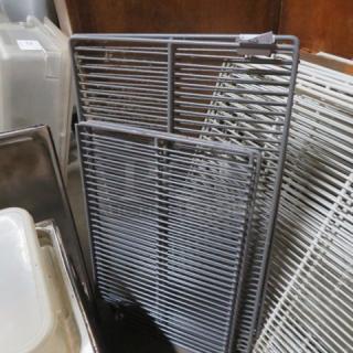 Assorted size wire racks in metal, various conditions, stacked against a wooden background; labeled 4XBID.