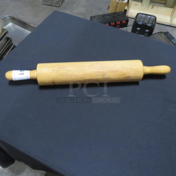 Wooden rolling pin with smooth finish and two handles, minor wear visible, auction tag attached to one handle.