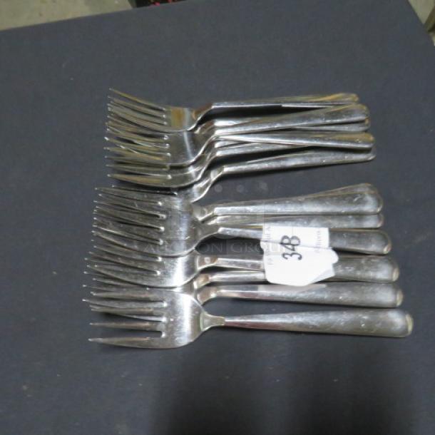 One lot of 15 silver serving forks, stacked, with a “38” label, in good condition, suitable for formal dining.