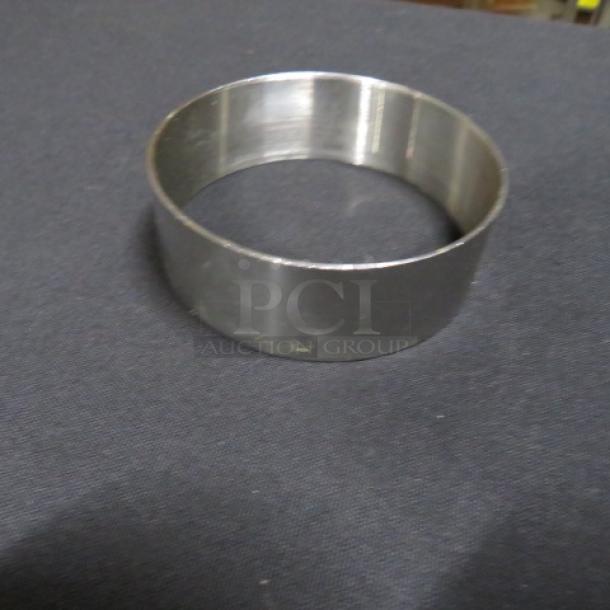 Stainless steel egg ring, model 12XBID, in good condition on a dark surface.