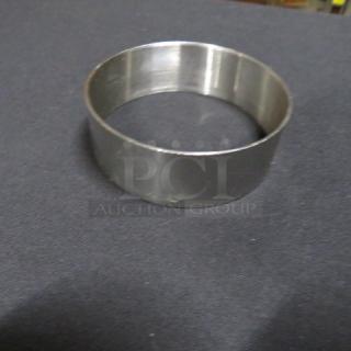 Stainless steel egg ring, model 12XBID, in good condition on a dark surface.