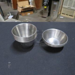Assorted stainless steel condiment cups, new condition, stackable set of seven, ideal for professional kitchen use.